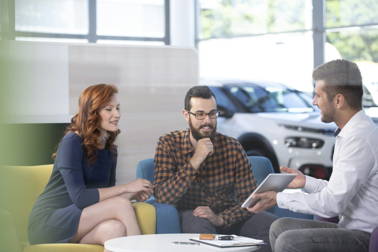 car dealer showing an offer to his happy clients in a car showro